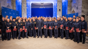 Zdjęcie przedstawia policjantów pozujących do zdjęcia z mężczyzną ubranym w garnitur.