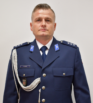Zdjęcie przedstawia policjanta w granatowym wyjściowym mundurze.