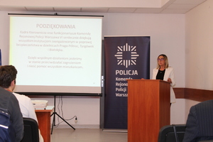 Zdjęcie przedstawia kobietę przy mównicy.