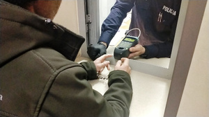 policjant wykonuje daktyloskopię u zatrzymanego