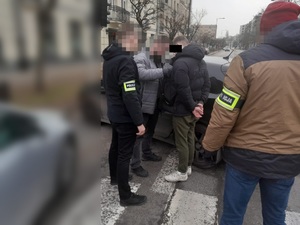zdjęcie przedstawia trzech policjantów stojących z zatrzymanym mężczyzną.