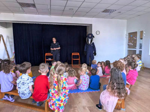 Zdjęcie przedstawia policjantkę i maskotkę Borsuka stojących przed dziećmi.