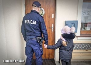 Zdjęcie przedstawia policjanta trzymającego za rękę małą dziewczynkę.