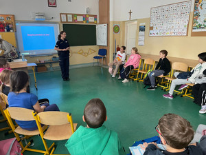 Policjantka stoi przed uczniami siedzącymi w klasie.