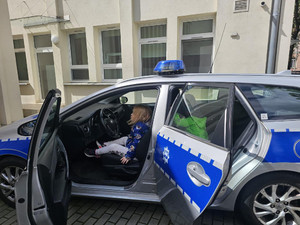 Zdjęcie przedstawia dziewczynkę siedzącą w radiowozie.