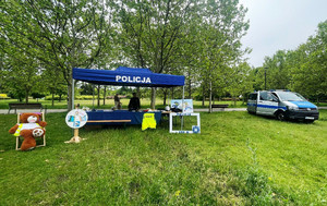 Zdjęcie przedstawia policyjne stoisko i radiowóz.