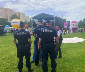 Zdjęcie przedstawia trzech policjantów idących wśród ludzi.