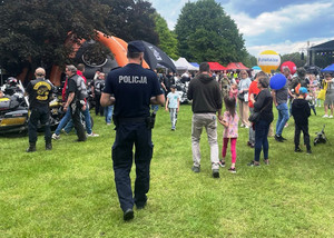 Dzielnicowy idzie wśród uczestników imprezy plenerowej.