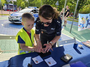 Policjantka wykonuje odcisk palca dziecka.