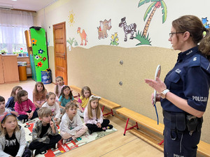 policjantka prezentuje dzieciom tarczę do zatrzymywania pojazdów.