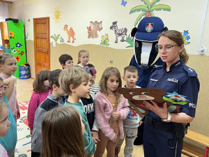 policjantka ogląda pracę plastyczną.