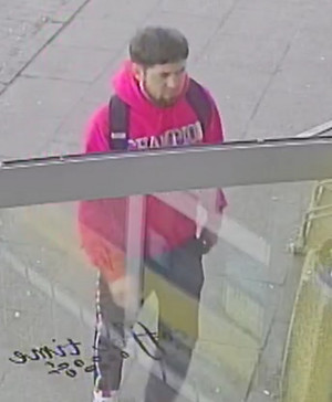 Zdjęcie przedstawia mężczyznę o ciemnym zaroście na brodzie ubranego w różową bluzę.