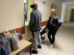 Policjantka pilnuje mężczyznę stojącego przy okienku do sprawdzania tożsamości.