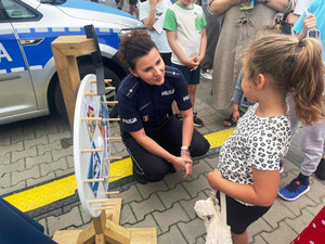 Policjantka kuca koło małej dziewczynki.
