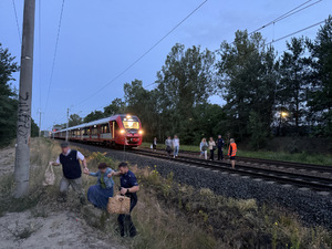 Policjant pomaga kobiecie przejść przez nasyp kolejowy.