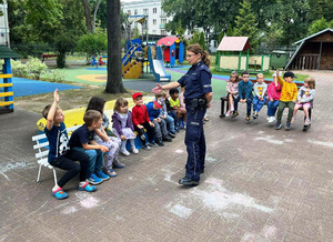 Zdjęcie przedstawia policjantkę z dziećmi na szkolnym patio.