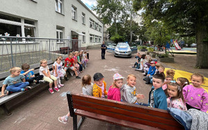 Zdjęcie przedstawia policjantkę z dziećmi na szkolnym patio.