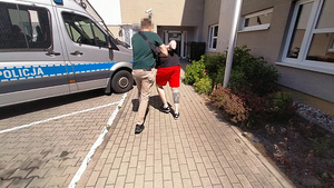 Policjant prowadzi zatrzymanego.