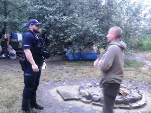 Zdjęcie przedstawia policjanta rozmawiającego z mężczyzną.