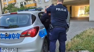 Zdjęcie przedstawia policjanta umieszczającego zatrzymanego w radiowozie.