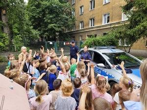 Zdjęcie przedstawia policjantów stojących przy radiowozie razem z dziećmi.