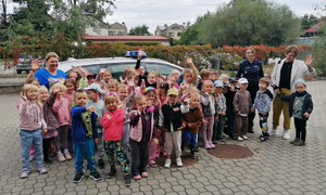 Policjantka razem z dziećmi i personelem przedszkola uśmiecha się do zdjęcia.