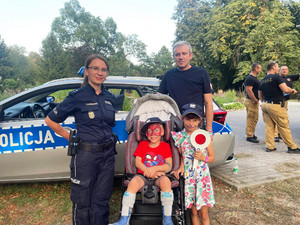 Zdjęcie przedstawia policjantkę stojącą przy tacie z dziećmi.