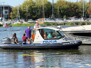Zdjęcie przedstawia osoby płynące policyjną motorówką.