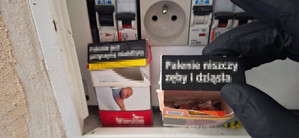 Zdjęcie przedstawia paczkę papierosów, a w niej zawiniątka.