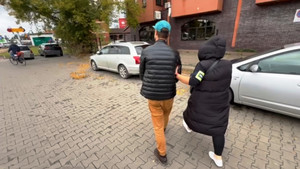 Zdjęcie przedstawia policjantkę prowadzącą zatrzymanego mężczyznę.