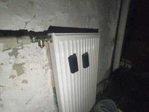 Zdjęcie przedstawia czarne pudełko przyklejone do kaloryfera.