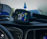 Zdjęcie przedstawia wnętrze samochodu z fragmentem czapki policyjnej z białym daszkiem leżącej na kokpicie oraz wideorejestratorem.