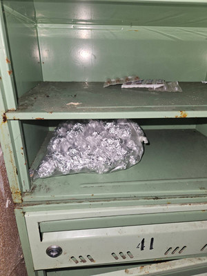 Zdjęcie przedstawia wnętrze skrzynki na listy, a w niej torebkę foliową ze srebrnymi zawiniątkami.