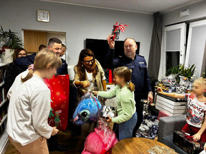 Zdjęcie przedstawia policjantów wręczających prezenty dzieciom.