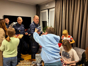 Zdjęcie przedstawia policjantów wręczających prezenty dzieciom.