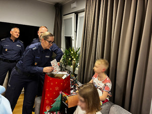 Zdjęcie przedstawia policjantów wręczających prezenty dzieciom.