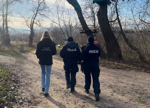 Zdjęcie przedstawia dwoje umundurowanych policjantów i kobietę idących ścieżką w rejonie Wisły.