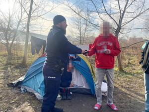 Zdjęcie przedstawia policjantów wręczających mężczyźnie koc termiczny.