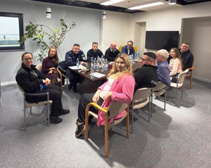 Zdjęcie przedstawia policjantów siedzących z innymi osobami przy stole.