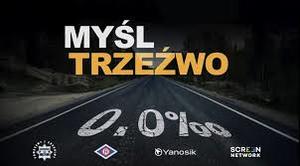 Zdjęcie przedstawia ciemny plakat na którym widnieje kolorowy napis: "Kierowco myśl trzeźwo".