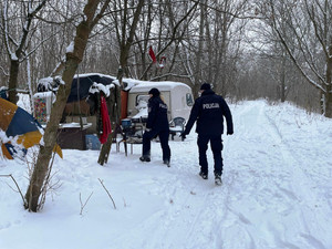 Zdjęcie przedstawia policjantów kontrolujących dzikie obozowisko.