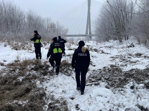 Zdjęcie przedstawia policjantów i strażników miejskich kontrolujących brzeg Wisły.
