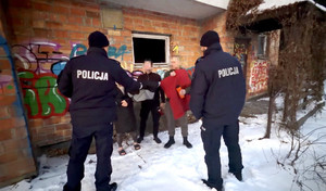 Zdjęcie przedstawia dwóch policjantów, którzy wręczają kurtki zimowe i termosy trzem osobom.