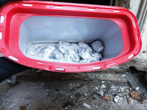 Zdjęcie przedstawia czerwony pojemnik, który zawiera zawiniątka z folii aluminiowej.