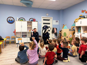 Policjant siedzi przed dziećmi.