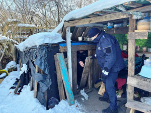 Zdjęcie przedstawia policjanta kontrolującego prowizoryczne pomieszczenie.