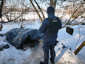 Zdjęcie przedstawia policjanta kontrolującego prowizoryczne pomieszczenie.