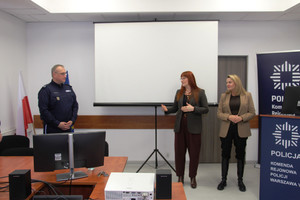 Zdjęcie przedstawia policjanta stojącego niedaleko dwóch kobiet.