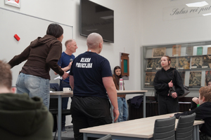 Zdjęcie przedstawia uczniów w pomieszczeniu, którzy odgrywają scenę.