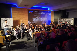 Zdjęcie przedstawia uczniów stojących na scenie i publiczność.